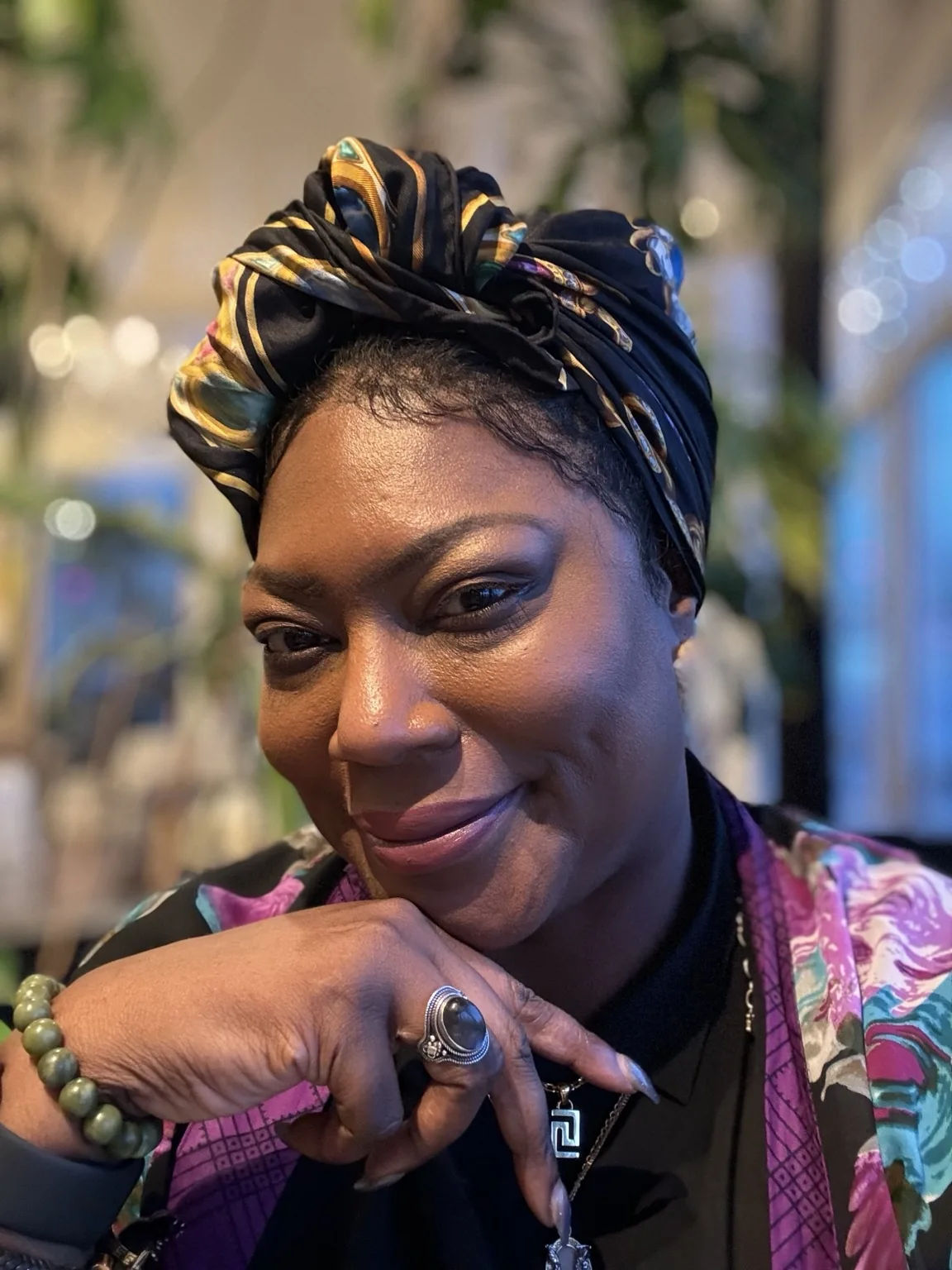 Maison Jet founder wearing a colorful silk headwrap and statement jewelry